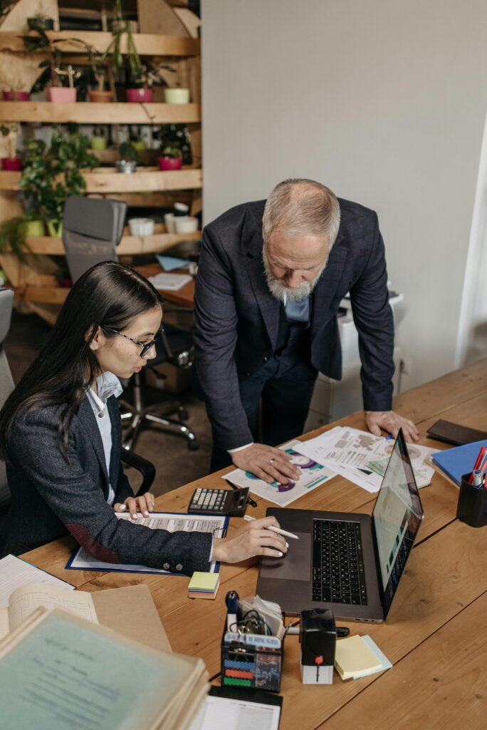 Business professionals collaborating over documents and laptop in a modern office.